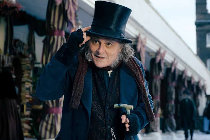 Johnny Depp caracterizado como Ebenezer Scrooge em cenário gótico e vitoriano