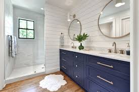 White and blue bathroom boasts a blue vanity adorned with gold pulls topped with gray quartzite fitted with a rectangular white porcelain sink and a gold faucet placed below a wood herringbone mirror alongside a white hex tiled. 8 Navy Blue Bathroom Vanity Ideas The Plumbette
