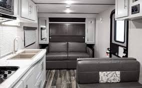 An angled double sink at the kitchen area with a refrigerator and a three burner. 8 Excellent Travel Trailers With Murphy Beds Rving Know How