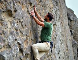 Fisheye editorial photograph of a male boulderer hanging from a ...
