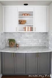 Medium tone wood floor white kitchen cabinets and white countertops with brass hardware. Two Toned Gray And White Cabinets Marble Subway Tile Carrara Countertops A Big Farmho Trendy Kitchen Backsplash Trendy Farmhouse Kitchen Trendy Kitchen Tile