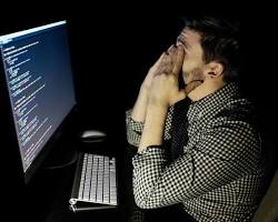 software engineer sitting at a computer, looking stressed