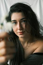 A woman is holding a flower and looking at the camera photo