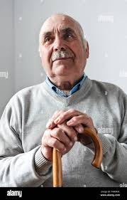 Nostalgic elderly man with a walking cane or stick sitting thinking