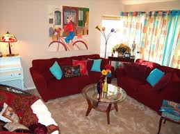 To create a unified design, look for ways to incorporate other small burgundy accents throughout the room. Living Room Maroon Sofa Blue Cushion Sofa Stand Light Round Coffee Table Yellow Flo Bohemian Living Room Decor Boho Chic Living Room Bohemian Style Living Room