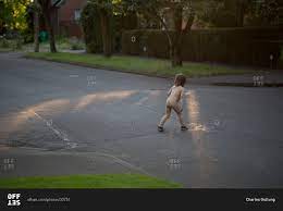Funny naked little child crossing the street stock photo 