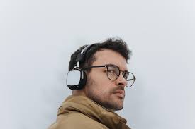 Rear view of handsome smart male listening to audio book using his  headphones and mobile phone messaging via social networks using bluetooth  connection during walk in the misty park people concept |