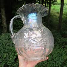 Carnival glass, pressed glass with an unmistakable iridescent glaze, peaked in production during the 1920s with a variety of shapes, patterns, and colors. Antique Dugan White Floral Grape Carnival Glass Paneled Water Pitcher Carnival Glass