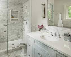 Borders are used to frame a tiled area, adding a luxurious and artistic appearance. Light Gray Washstand With Marble Chair Rail Transitional Bathroom