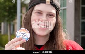 A happy vaccinated teenager (16 year old) smiles and shows off her "I got  my Covid-19 vaccine" sticker Stock Photo