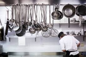 See kitchen background stock video clips. Utensils On Metal Rack With Chef Cooking In Background At Commercial Kitchen Stock Photo Dissolve