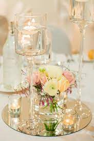 Add some reflection to your wedding centerpieces! Floating Candle Centerpiece On A Round Mirror Base With Fresh Flowers Floa Candle Wedding Centerpieces Wedding Table Centerpieces Floating Candle Centerpieces