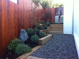 A grass path through a rock garden featuring a large rock fountain. Garden Landscaping Ideas For Borders And Edges