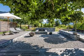 Ein Grosser Sitzplatz Mit Naturlichem Geplatscher Vom Wunderbaren Brunnen Im Zentrum Dieser Garten Ladt Zum Verweil Gartengestaltung Feuerstelle Garten Garten