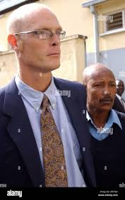 Thomas Patrick Gilbert Chlomondely, left, a Kenyan national of British  descent, escorted by a police officer is brought to the Nakuru Court,  Kenya, Thursday, April 28, 2005. Chlomondely was charged Thursday with