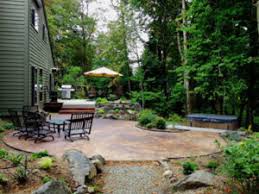 A rustic meets boho balcony with dark stained furniture, a wicker floor lamp and much greenery. Cedar Mills Woodland Low Maintenance Garden Design Landscape Design In A Day