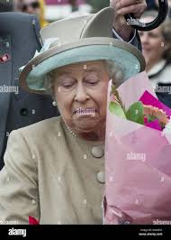 Britain's Queen Elizabeth II pulls a face as a bunch of flowers are pushed  too near to her face during a visit to the Australian War Memorial in the  capital Canberra, in