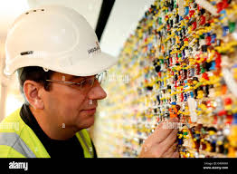 LEGOLAND Windsor model maker Neville Smith puts the finishing touches to a  wall made up of over 6000 Lego figures. The wall is situated in the  Reception area of the resort's new