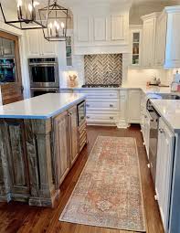The white kitchen cabinets help to brighten and lighten up the space. Cc And Mike Labor Day Sales Terracotta Loren Rug In A Beautiful White Kitchen With Natural Wood Island And Quartz Countertops And White Kitchen Cabinets With Brick Backsplash And Silver Hardware