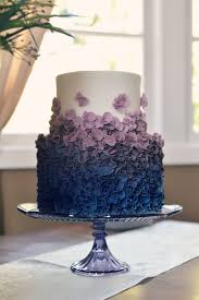 The design to the left is a three tier wedding cake with a fountain.the wire and royal spray on top adds even the water is colored blue, and flowers surround it. Modern Elegant Wedding Cake With Ruffles Ombre From Royal Blue To Purple Country Cake Shop Purple Wedding Cakes Modern Wedding Cake Royal Blue Wedding Cakes