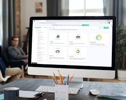 Image of person sitting at a desk looking at a computer screen with a line graph and a pie chart on it