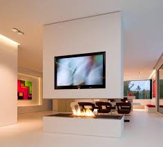 Get inspired by 10 living rooms with fireplaces. A Minimalist Room Divider Incorporates A Tv And Open Fireplace In This Home