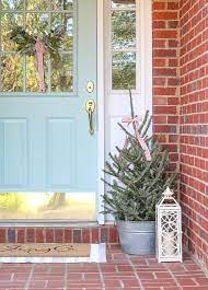 A length of greenery garland hung over porch windows creates a beautiful frame for the christmas tree lights peeking through the panes. Christmas Decorating Ideas For Porches And A Home Tour