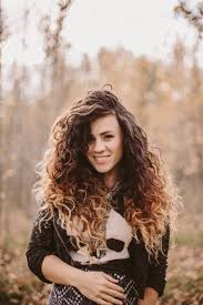 Intriguing, tempting lady with curly long hair lowered her eyes shyly, holding champagne glass in her hands, posing while sitting on elegant sofa. 15 Best Curly Hair Tips For Beautiful Healthy Curls Glamour