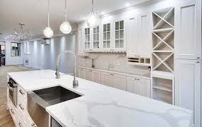 This gorgeous white quartz is used on a tradition kitchen, paired with off white cabinetry, farmhouse sink, and a white and grey mix of bricks as a backsplash. Calacatta Quartz Countertops Design Guide Designing Idea