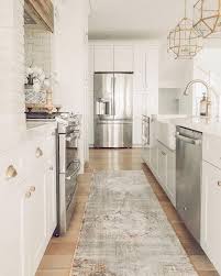 White Kitchen With Brass Pendants And Hardware Kitchen Rug Runner Brick Hood Coastal Farmhouse S Rug Runner Kitchen Coastal Farmhouse Kitchen Kitchen Rug