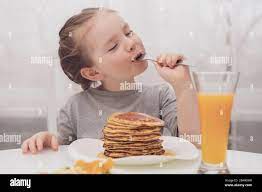 Milaya malen'kaya devochka yest bliny i zakrytymi ot udovol'stviya  glazami69/5000Cute little girl eating pancakes and eyes closed with  pleasure Stock Photo - Alamy