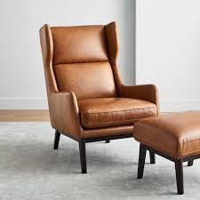 The chair has ruched arms with metal tufting, and rests on caster feet. Ryder Leather Chair Ottoman Set