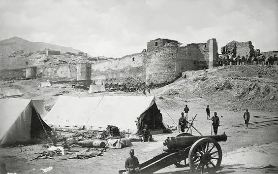 Photograph John Burke 1879, 2nd Afghan War (1878-80), with a view of the damaged Bala Hissar fortress at Kabul in Afghanistan showing soldiers posed in the foreground and camels being led into