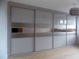 Chic walk in closet boasts floor to ceiling wardrobe cabinets accented with mirrored doors alongside white drawers adorned with brass knobs. Fitted Sliding Wardrobes Custom Made Installed Birmingham