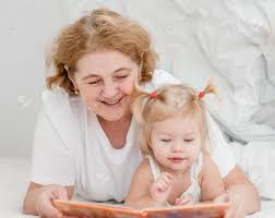Baby Girl And Grandmother Reading A Book On The Bed. Stock Photo ...