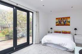 White walls and plush bedding give the space a clean, airy look and feel while three large windows and a custom garage door let in an abundance of natural light. 10 Garage Conversion Ideas