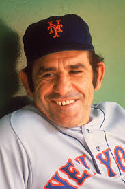 New York Mets' manager Yogi Berra sits and smiles during a game at Shea  Stadium, c1970.