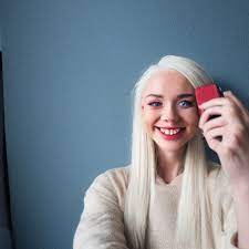 prompthunt: Selfie of a cute petite young woman smiling into the camera  with long platinum blonde hair, light blue eyes, bisque skin tone, cute  freckles, red blush, smiling smugly, small face, wearing