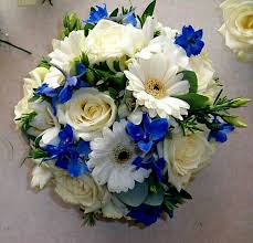 Brightly colored gerbera daisies are beautiful in any arrangement. Blue Delphinium White Roses White Gerbera Daisies Green Eucalyptus Wedding Bouquet Flower Bouquet Wedding Blue Wedding Flowers Winter Wedding Flowers
