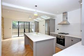 Neutral palette kitchen with light gray textured drawers, recessed lighting, hardwood floors, and a huge window allowing a lot of sunlight. Kitchen Window Ideas Porcelanosa Trendbook