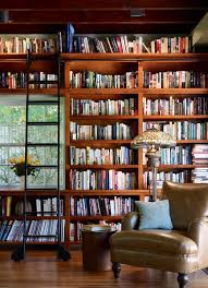 A modish home library with stylish bookshelves and an elegant black center table on top of a red rug set on the hardwood flooring. 50 Most Jaw Dropping Home Library Design Ideas