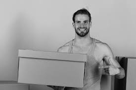 Mann Unter Kästen Zeigend Auf Seine Genitalien Bedeckt Durch Karton  Stockfoto