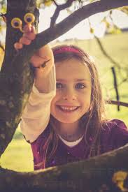 Portrait of smiling little girl climbing in a tree stock photo