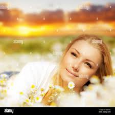 Beautiful woman enjoying daisy field at sunset, nice female lying down in  the meadow of flowers, pretty girl relaxing outdoor, happy young lady and  sp Stock Photo