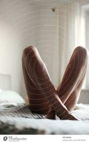 nackte, große, schlanke Frau liegt im Bett und überkreuzt die Beine so,  dass man nur die Beine sieht - ein lizenzfreies Stock Foto von Photocase