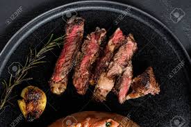 A rib eye steak gets its name from the location of the cut, the cow's upper rib cage, and the fact that it is boneless, which makes it an eye in meat cutting terminology. Rib Eye Steak Garnished With Baked Sweet Potato Grilled Beef Organic Farm Meat Black Background Stock Photo Picture And Royalty Free Image Image 139668645