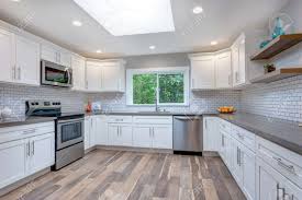 They make use of stools in this particular kitchen, and it's as vibrant as any white kitchen space could be. Open Concept Kitchen With White Cabinets Grey Quartz Countertops And Tile Backsplash Stock Photo Picture And Royalty Free Image Image 104976947
