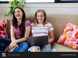 Candid image of teenage girls with cell phones and computer watching or  surfing the internet stock photo - OFFSET