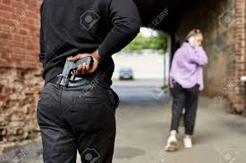인식할 수 없는 남자가 총을 들고 거리에서 혼자 걷는 젊은 여성을 따라가는 뒷모습 여성 강간 개념 실제 사람들은 손에 집중하는 모습  로열티 무료 사진, 그림, 이미지 그리고 스톡포토그래피. Image 174779791