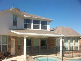 This patio in a home by aamir khandwala is covered with a white one that compliments the deck for a modern approach that pops against the green landscape. Houston Covered Patios Lone Star Patio Builders